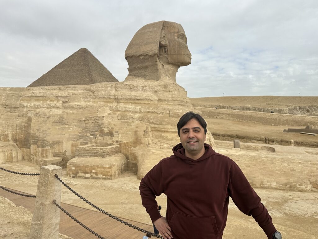 Ryan Montazer at the Great Sphinx of Giza, with a pyramid in the background, Egypt